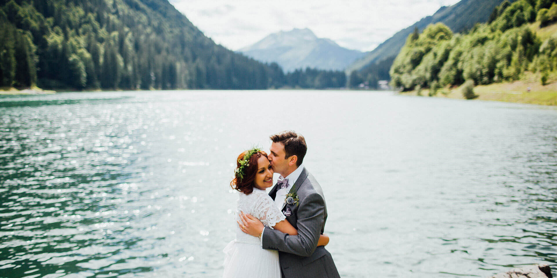 bride and groom kissing on their lake side wedding in the alps